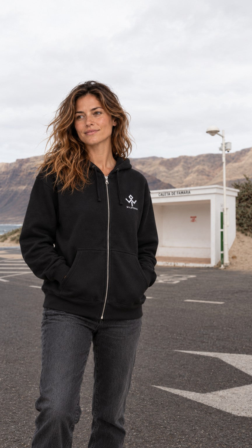 Sudadera Wild Tribu Essential negra con cremallera y logo bordado, sobre modelo en Famara